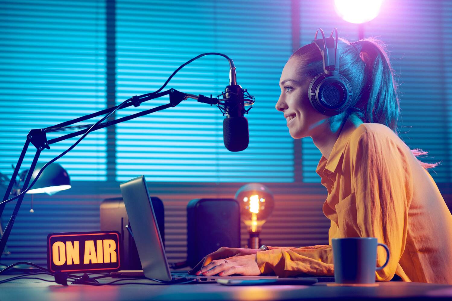 A broadcaster in headphones speaking into a microphone in her home studio